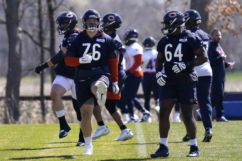 Chicago Bears offensive linemen Teven Jenkins, left, and Willie Wright warm up with teammates during the team's voluntary minicamp on April 21, 2022.