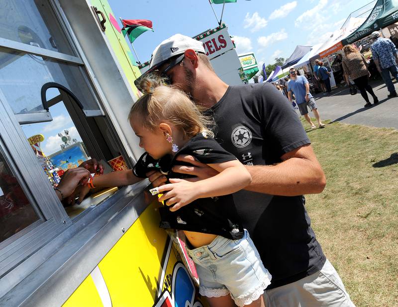 Dad Blake Carpenter of Montgomery lifts his daughter 3-year-old Shawna, to get the unlimited ride wristband at Hometown Days on Sunday, Sept. 1, 2024, at Beecher Park in Yorkville.
