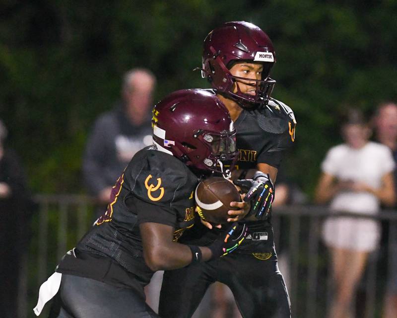 Montini Catholic's Israel Abrams, left, hands the ball off to teammate Isaac Alexander (28) during the game against Fenwick on Friday Sept. 19, 2025, held at Montini High School.