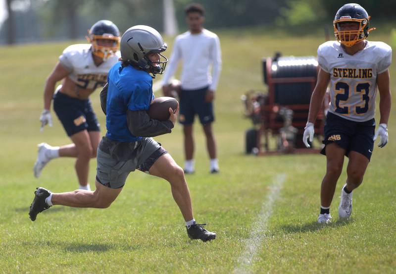 Oswego East quarterback Niko Villacci runs the ball during a joint practice with Sterling and Glenbard South football teams on Tuesday, July 15, 2025 in Oswego.