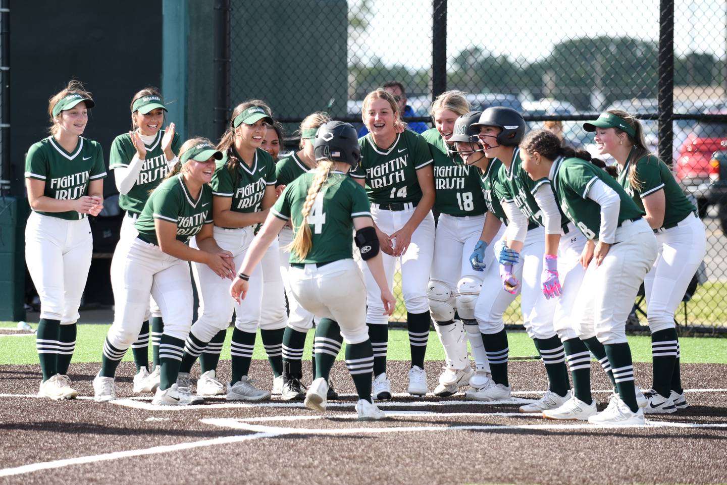 The Bishop McNamara softball team greets Teagan McCue (4) at home plate after her home run in the Class 2A Coal City Regional championship Friday, May 23, 2025.