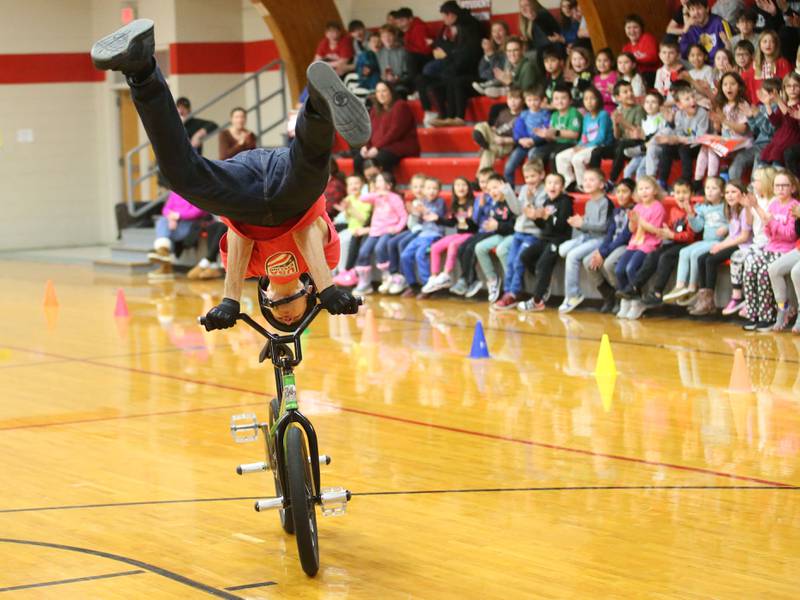 Matt Wilhelm, a national BMX Rider, Guinness World Record holder and America’s Got Talent semi-finalist rides a bicycle hanging upside down during an assembly on Monday, Jan. 13, 2024 at Ladd Grade School. Wilhelm, a three-time X Games medalist and two-time national champion, is a native to Oak Lawn. Wilhelm was bullied as a child. Today, he presents a strong message while speaking to children while focusing on kindness, positivity and the differences that one person can make.