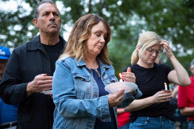 Connie Salamone of St. Charles shields a candle from the wind during a candlelight vigil at the Kane County Courthouse in Geneva on Wednesday, July 6, 2022. The vigil was organized to honor the mass shooting at a Fourth of July Parade in Highland Park.