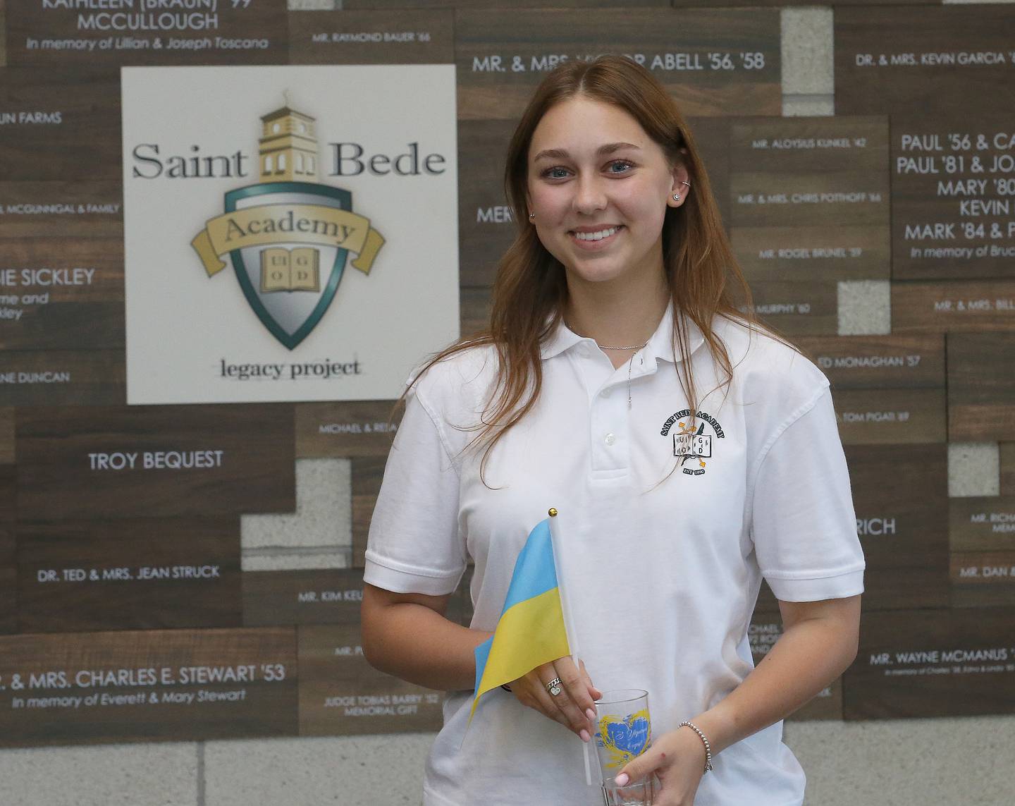 Anna Rudemko a refugee from Ukraine poses with a photo while holding the Ukraine flag on Thursday, Aug. 31, 2023 at St. Bede Academy. Rudemko is a student at St. Bede who wanted to come to a school that she could feel welcome and exceed while her country is at war with Russia.