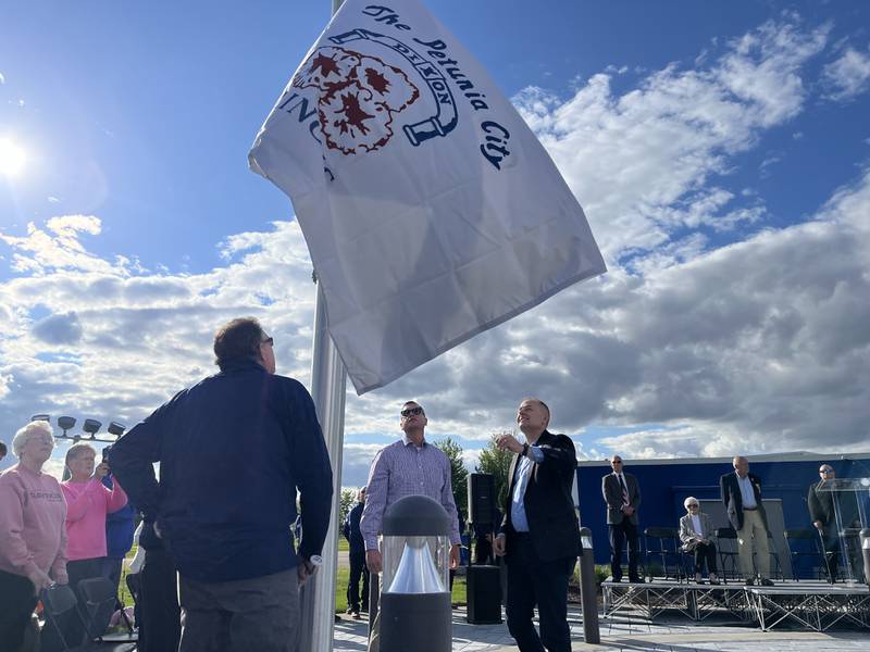 Dixon City Manager Danny Langloss (right) and Dixon Fire Chief Ryan Buskohl (middle left) watch as Dixon's Petunia City flag is hoisted up in the air at Raynor's ceremonious flag-raising event Thursday, May 22.