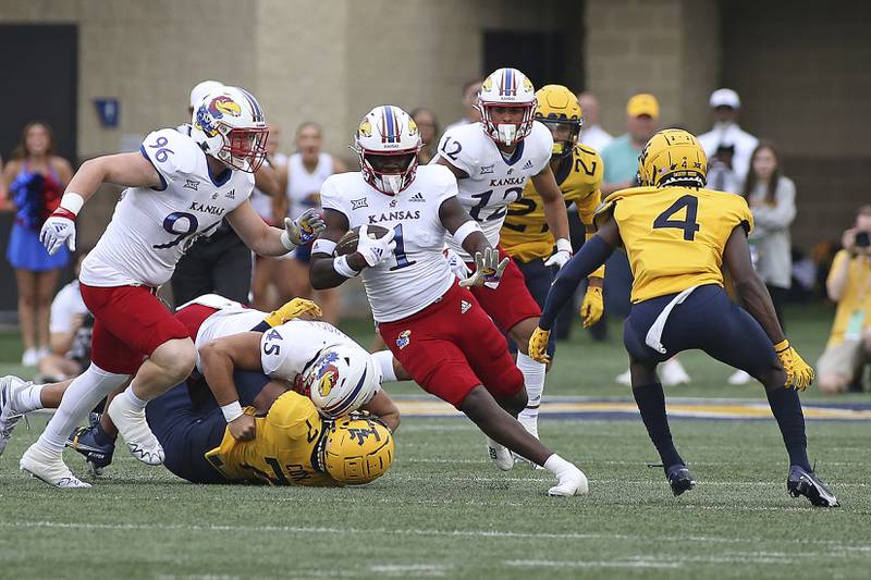 Kansas safety Kenny Logan Jr. (1) is defended by West Virginia Mountaineers cornerback Rashad Ajayi (4) during the first half of an NCAA college football game in Morgantown, W.Va., Saturday, Sept. 10, 2022. (AP Photo/Kathleen Batten)