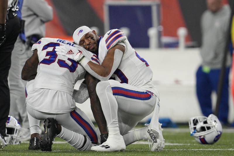 Buffalo's Siran Neal (left) is comforted by Nyheim Hines react after teammate Damar Hamlin collapsed during the first half against the Cincinnati Bengals, Monday, Jan. 2, 2023, in Cincinnati.