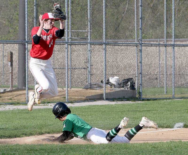 Streator's Blaize Bressner leaps in the air to catch the ball as Seneca's Aidan Vilcek slides into the bag safely on Friday, April 19, 2024 at Seneca High School.