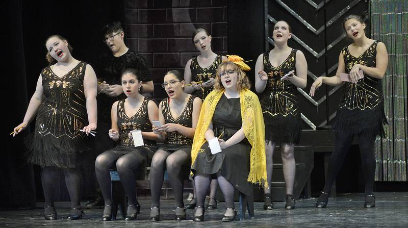 (Back from from left to right) Streator High School students Max Fraga, as Fred Casely; Izabella Dean, Keirsten Burgess, Abby Mascal, (front) Gracie Drysdale as Mona; Lily Michael, Ariadna Gauna and Elizabeth Abbott as Mary Sunshine rehearse a scene from their spring musical "Chicago."