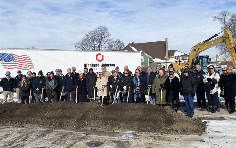 DeKalb area officials including elected leaders, staff and supporters of Safe Passage Inc., pose for a group photo on Friday, Dec. 5, 2025, at the agency's ceremonial groundbreaking to mark the start of construction on a new domestic violence survivor shelter at 217 Franklin St., in DeKalb.