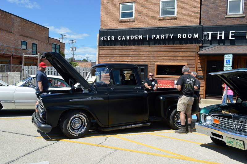 Bob Bass, of Franklin Grove (left), looks at the engine of a 1958 Chevy Apache while owner Adam Asbury, of Franklin Grove (center-left), Brandon Bass, of Dixon (right) and Rich Long, of Sterling, stand around the vehicle's cargo bed during the 35th annual Polo Car Show on Saturday, Aug. 10, 2024.