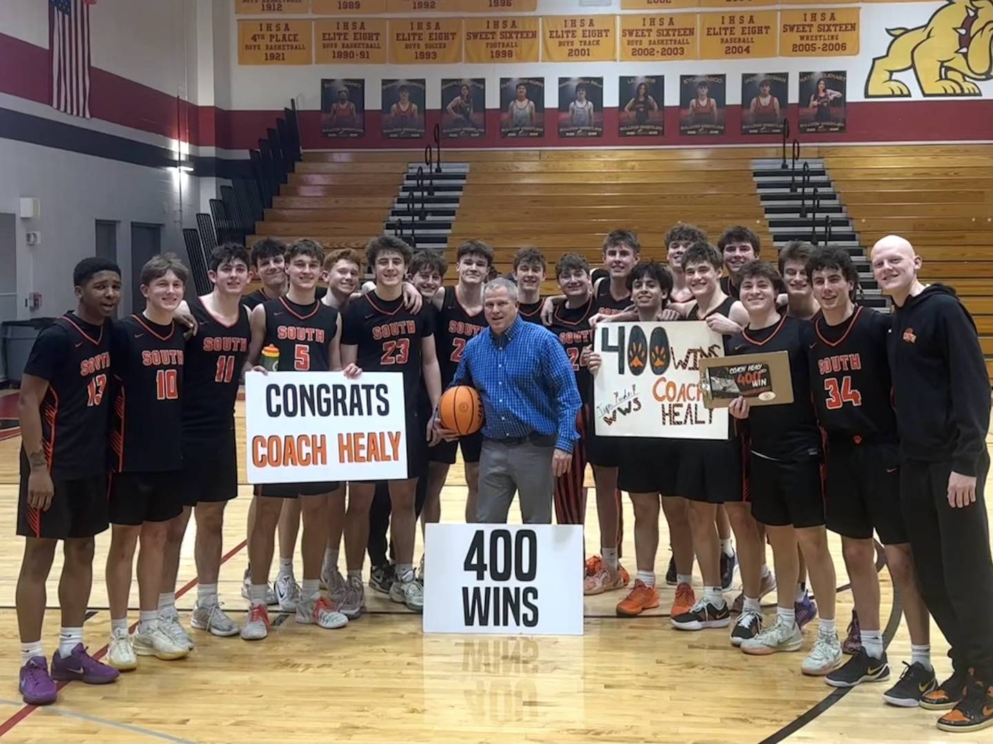The Wheaton Warrenville South boys basketball team celebrates with head coach Mike Healy after securing his 400th career win.