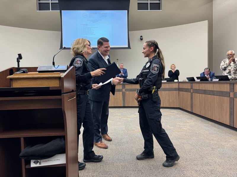 2023 Officer of the Year Sarah Markusic shakes hands with Morris Mayor Chris Brown and Morris Police Chief Alicia Steffes.