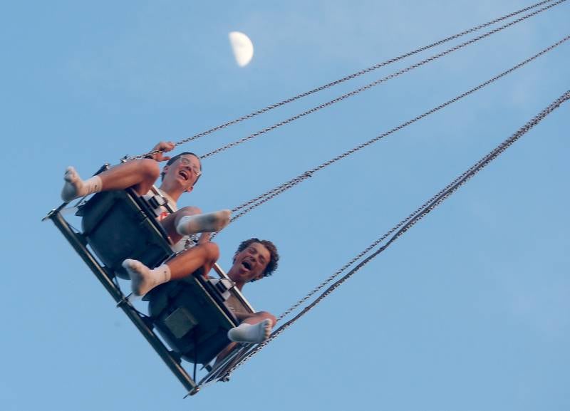 Collin Crew and Charlie Jeppson ride the swing ride as a crescent moon appears in the sky behind them during the  Summer Fun Fest on Friday, June 14, 2024 in Oglesby.