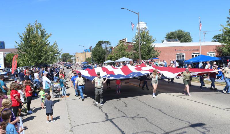 A large American Flag is carried by volunteers down Main Street during the 52nd annual Homestead Festival parade on Saturday, Sept. 9, 2023 in Princeton.