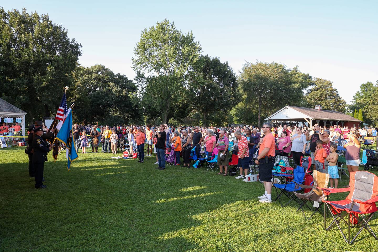 Attendees stand for the national anthem during the opening ceremony for National Night Out at Perry Farm Park in Bradley on Tuesday, Aug. 5, 2025.