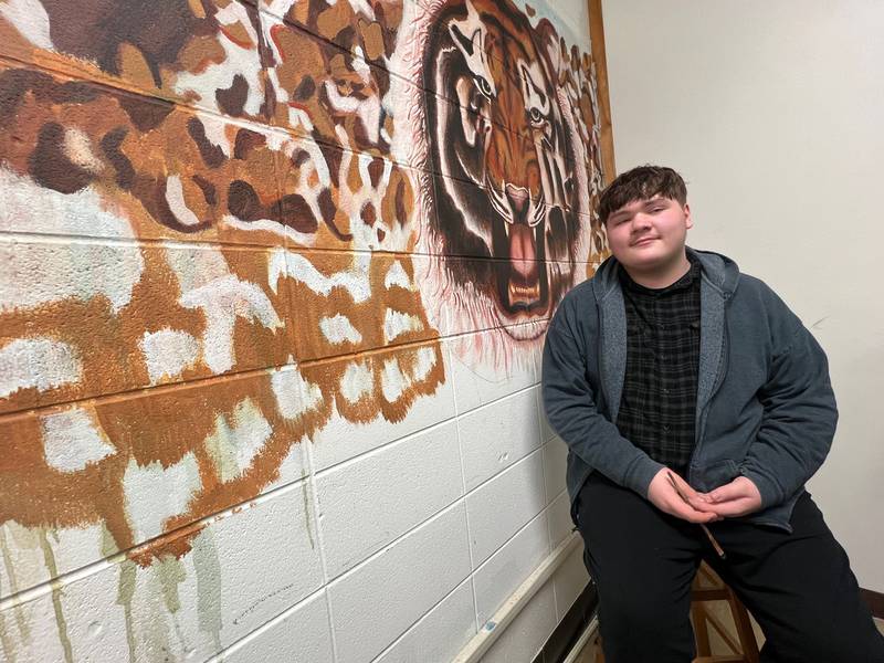 Justin Matlow, 15 and a sophomore at Joliet West High School, is freehandedly creating a tiger mural in English/journalism Jenn Galloy's classroom to serve as a backdrop for her students' regular Tiger News broadcast.
