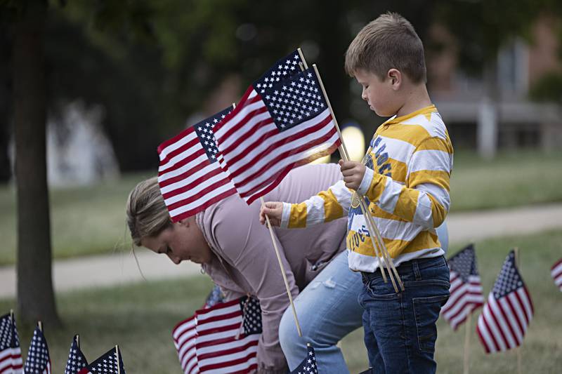 Angie Shippert and son Rocky, 6, work to plant flags on the lawn of the Old Lee County Courthouse in Dixon Wednesday, Sept. 6, 2023.