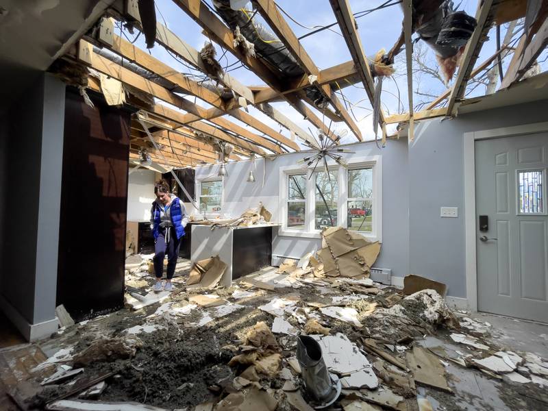 Emily LaVoie steps over debris in what was the kitchen at her Elmwood Drive home in Aroma Township on April 8, 2026. She and her husband, Dave Herberger,  are in the process of planning repairs for the damage caused by the EF-3 tornado about one month ago.