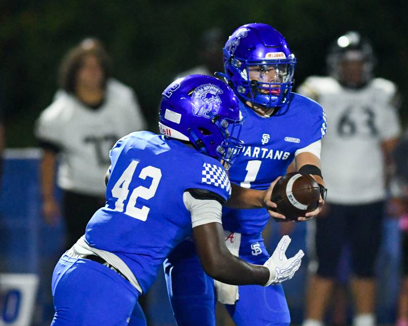 St. Francis's Brock Phillip (1) hands the ball off to teammate St. Francis's Tivias Caldwell jr. (42) during the game on Friday Oc. 3, 2025, while taking on IC Catholic Prep held at St. Francis High School.