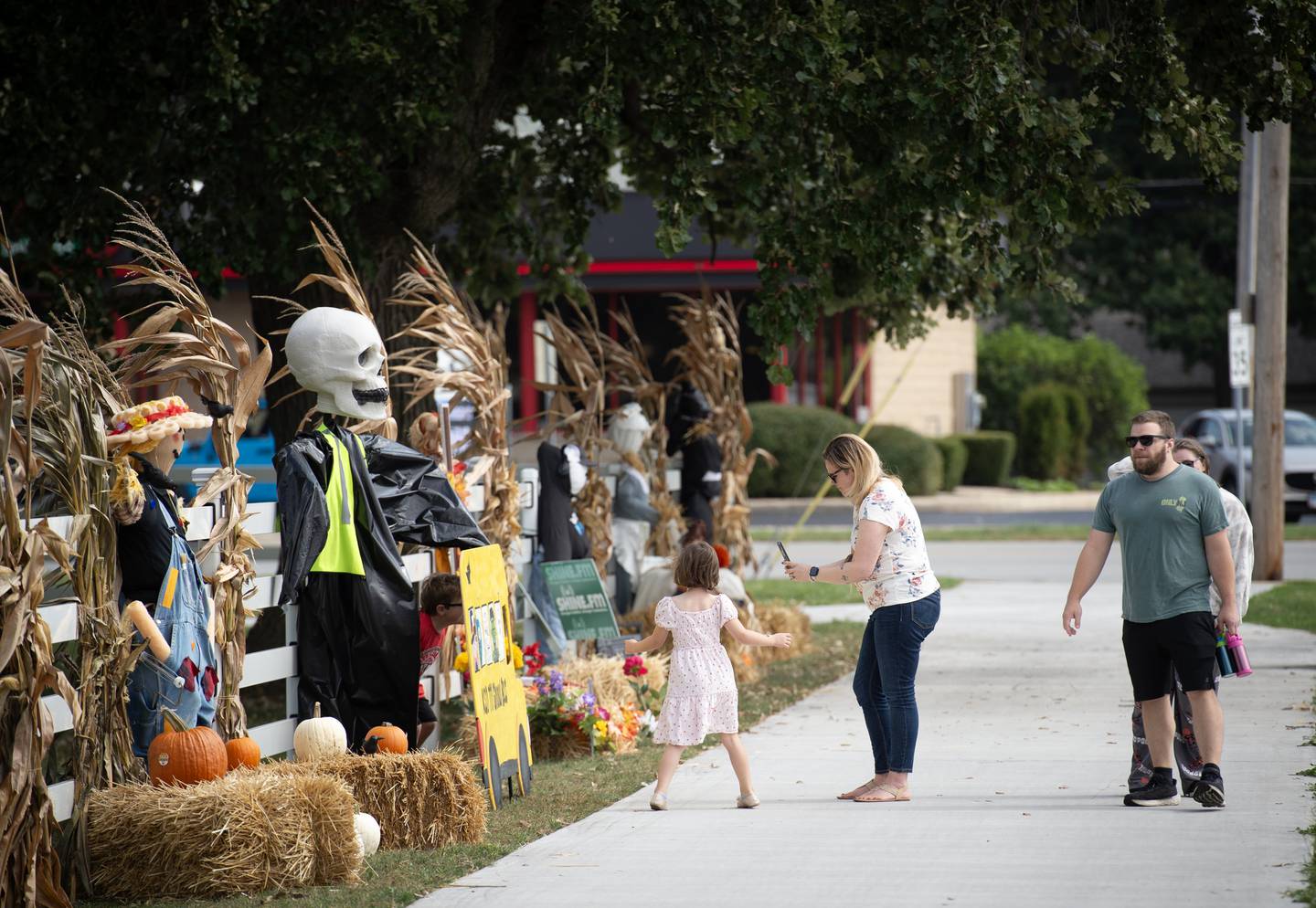 People stroll past the scare scrows on display at Perry Farm during the Fall Art Stroll and scare crow voting on Sunday, September 21, 2025.