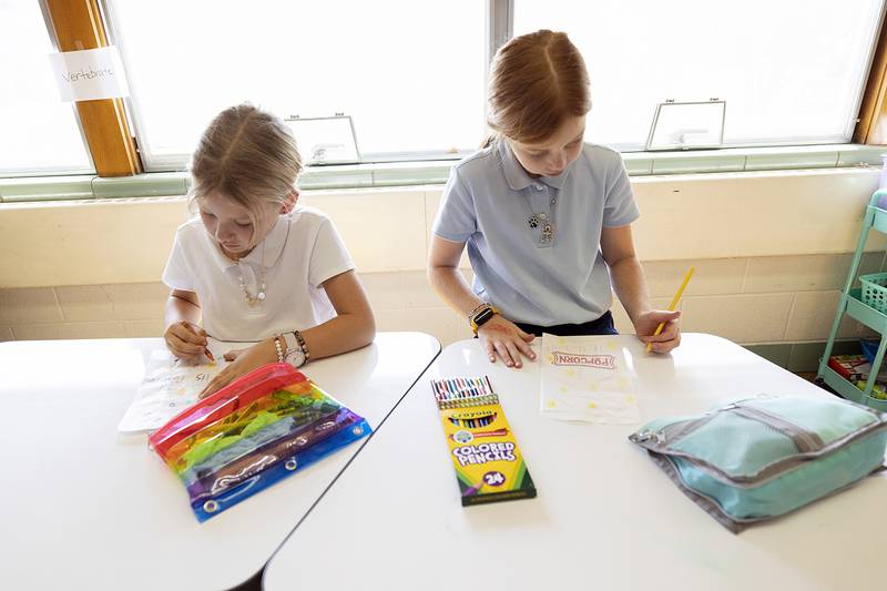 S. Anne’s second grader Katie Demmer (left) and fourth grader Lola Smith decorate popcorn bags Thursday, October 10, 2024, as part of the art and religion aspects of the STREAM event. The bags will be filled and delivered to local departments as a thank you gesture.