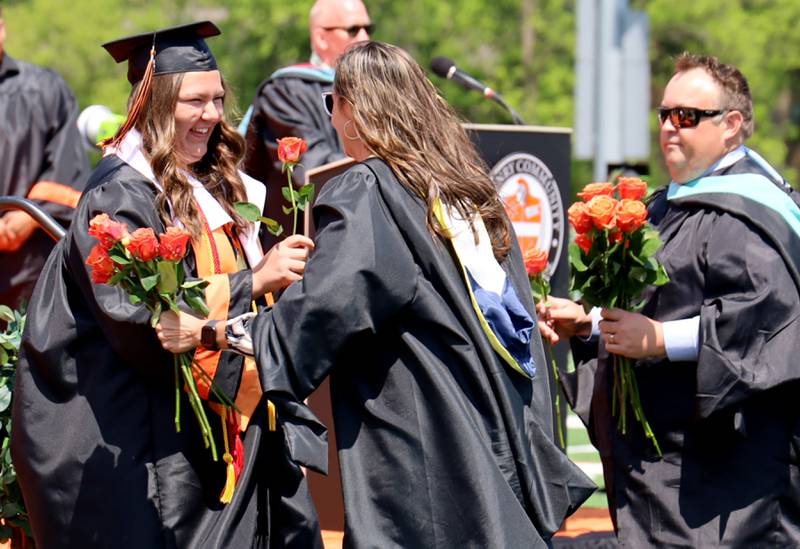 Graduate Lynette Alsot receives flowers from Dean Hilary Agnello Saturday, May 20, 2023, during the McHenry Community High School Graduation Ceremony for class of 2023 at McCracken Athletic Field in McHenry.