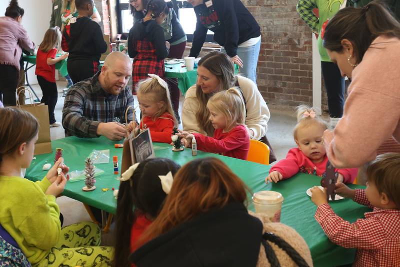 Pastor Cameron Graper (left) helps girls decorate Christmas trees during the Miracle on First Street at Ax Church on Saturday, Dec. 6, 2025 in La Salle.