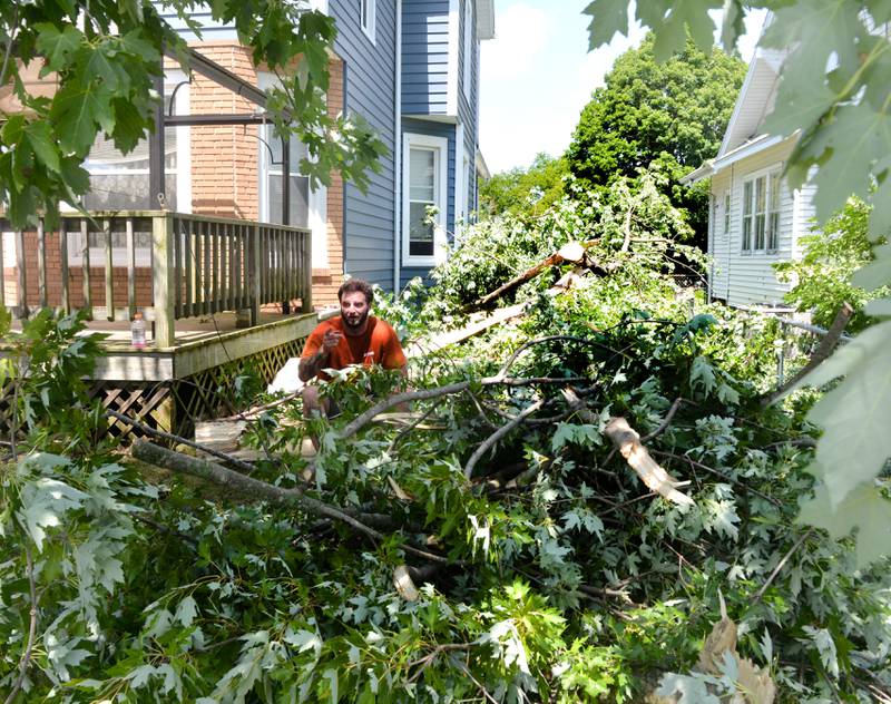 Dakota Murtha, 27, of Dixon, takes a much needed break from the heat after helping clear trees and branches felled by Friday's early morning storm that hit a portion of west Dixon. Murtha, a former Marine, and Al Detig, 62, also of Dixon, pitched in to help residents whose residences were affected by the storm.