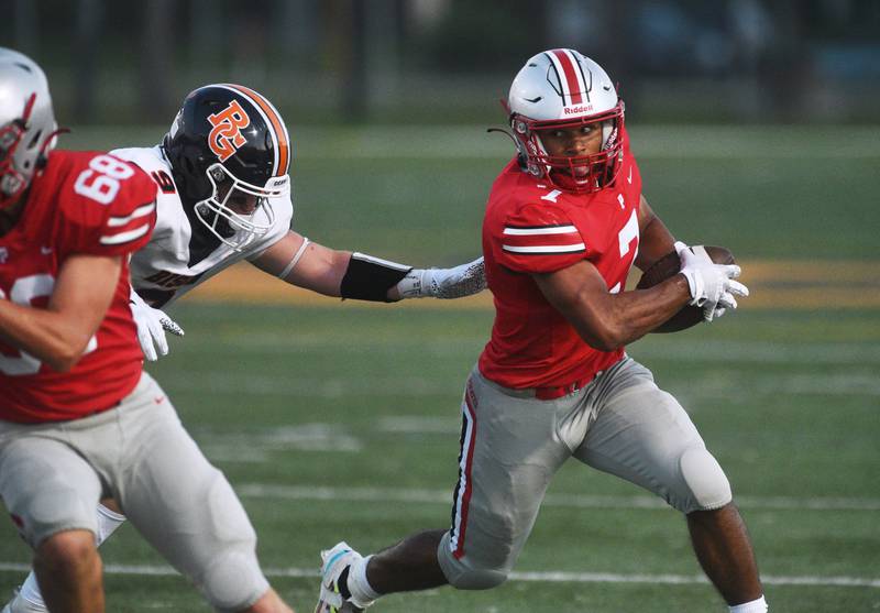 Palatine's Dominick Ball (7) looks for running room under pressure from Buffalo Grove's Gavin Lee (9) during Friday’s football game in Buffalo Grove.