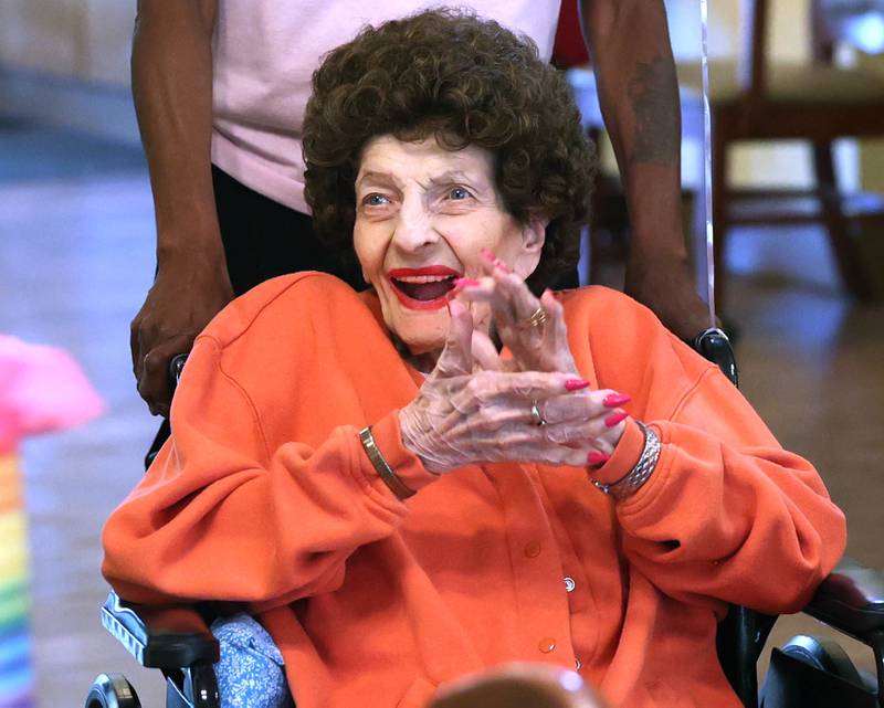 Claire Hubele, a resident at Heritage Woods of DeKalb, claps Wednesday, July 9, 2025, as she arrives for a party celebrating her 100th birthday.