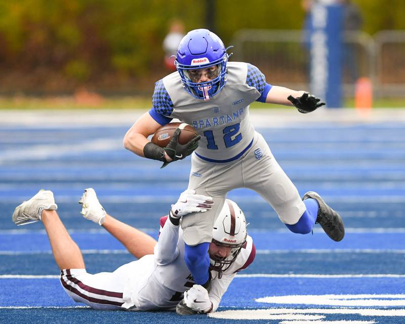 St. Francis's Dario Milivojevic (12) gains some yards before getting tripped up by Prairie Ridge's Logan Thennes (2) on Saturday Nov. 8, 2025, during the second round of the 5A playoff game held at St. Francis High School.