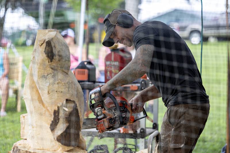 Joe Stebbing cuts into a hunk of wood Wednesday, August 6, 2025, during a chainsaw carving demonstration at the Carroll County Fair.