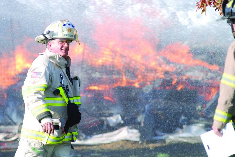 Ashton Fire Chief Bernard Richter confers will a Linn-Scott-Rock firefighter Thursday afternoon as crews douse a barn fire at 1884 S. White Rock Road in rural Rochelle. Eight departments responded to the blaze, ignited by a furnace that exploded and resulted in the owner being flown to OSF Saint Anthony Medical Center in Rockford with burns to 20 percent of his body, according to the Rochelle Fire Department.