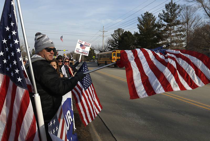 Chris Wilder, of Cary, waves a flag during a Cary School District 26 anti-mask rally Tuesday, Feb. 15, 2022, along Three Oaks Road at Cary-Grove Park. The event was attend by about 100 people and organized by the Illinois Parents Union Cary.