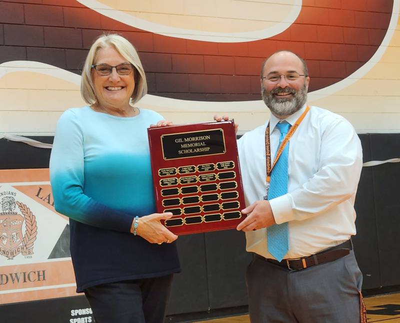 Jaye Morrison presents a plaque listing Gil Morrison Memorial Scholarship winners to Sandwich High School Principal Dr. Shane Darnell.