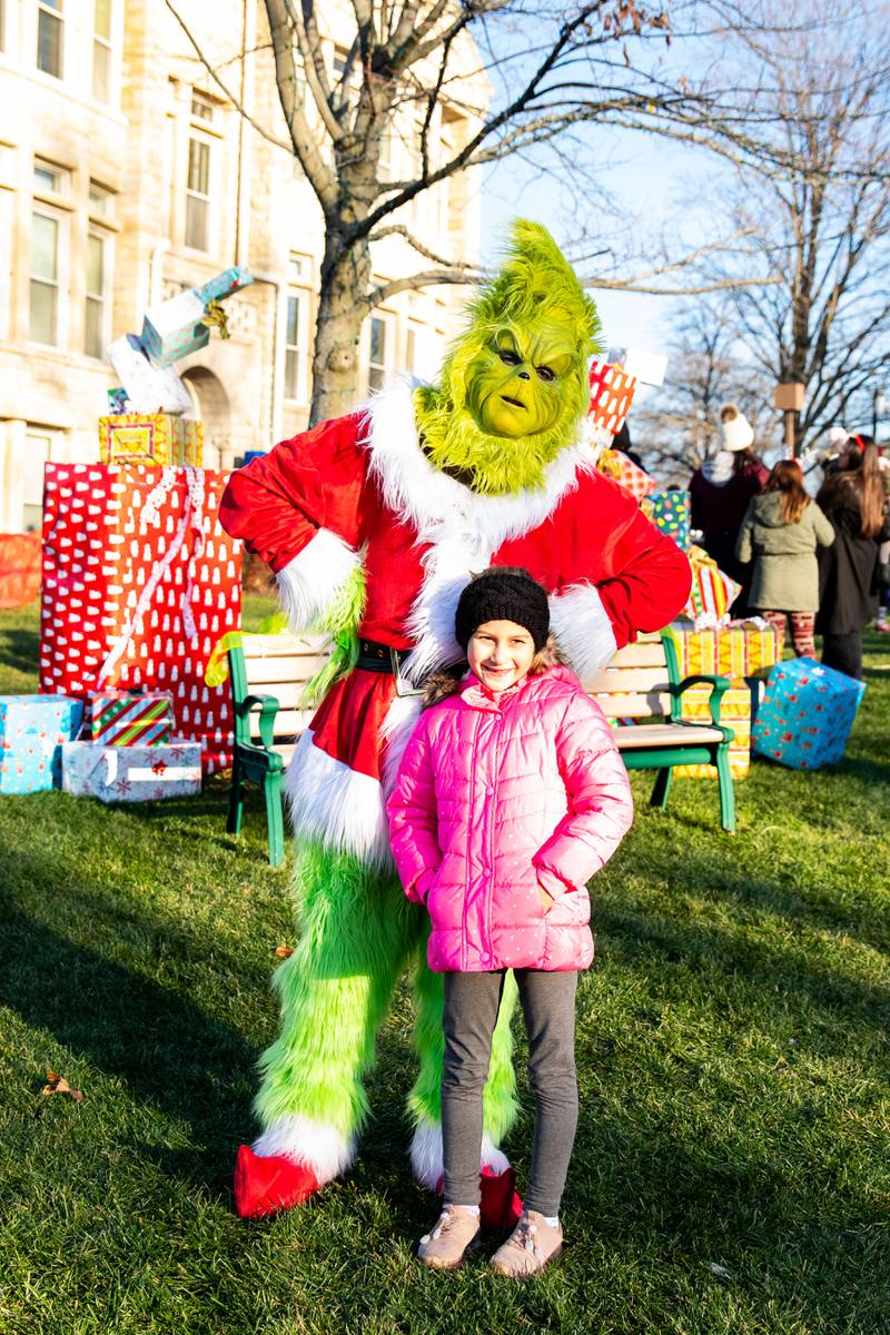 Liliana Tryba, of Homer Glen, takes a photo with The Grinch during Christmas in the Square in Lockport on Saturday, Nov. 25, 2023.