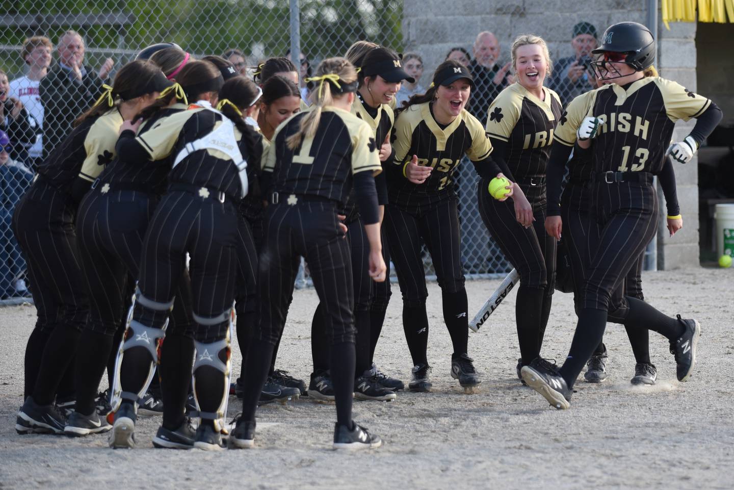 Bishop McNamara's Emma Thyfault (13) is greeted by her Fightin' Irish teammates at home plate after hitting a home run during a home game against Bradley-Bourbonnais Thursday, May 7, 2026.