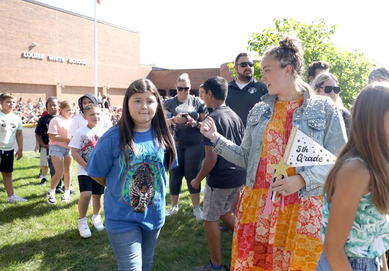 Fifth-grade teacher Josephine Neely encourages her students as they prepare to ring the school bell on the first day of school at Louise White Elementary in Batavia on Wednesday, Aug. 16, 2023.