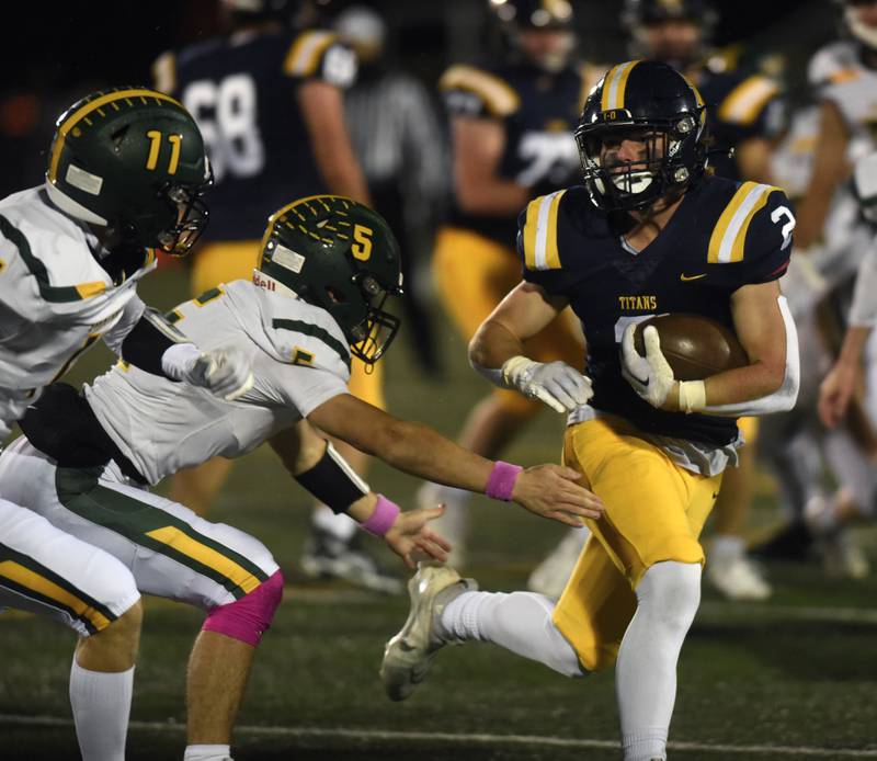 Glenbrook South’s Charlie Gottfred carries the ball as Glenbrook North's Jack Philbin (5) closes in to make the tackle during Friday’s game in Glenview.