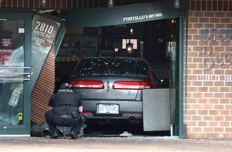 An Oswego Police officer photographs the scene Wednesday, July 30, 2025, where a car crashed through the front entrance of the Portillo’s at 2810 U.S. Route 34 in Oswego injuring 12.