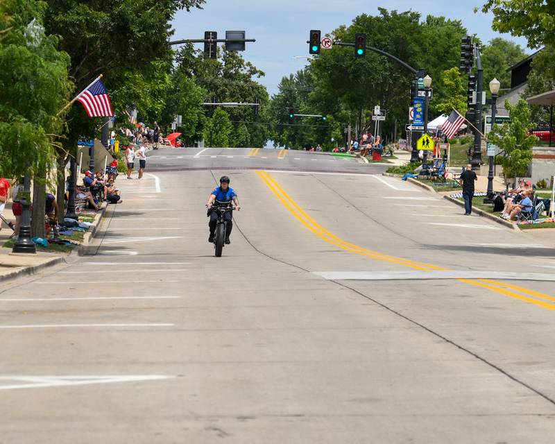 A police officer patrols the parade route along Main Street before the start of the Independence Day parade on Friday July 4, 2025, held in downtown Downers Grove.