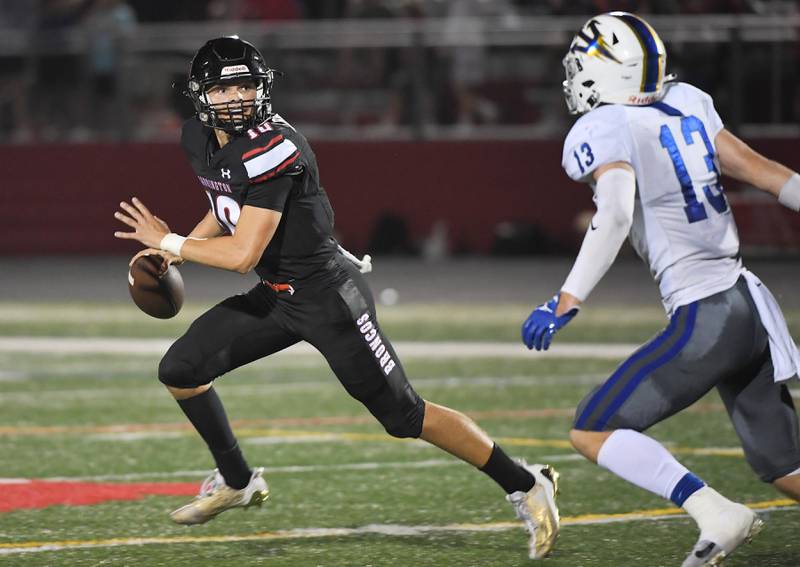 Barrington’s Nick Peipert rolls out as Warren’s Liam Wiley chases him at Barrington High School Friday, August 25, 2023.