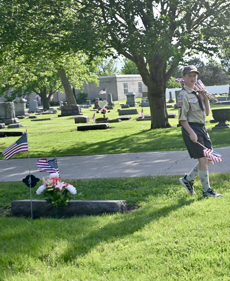 Boy Scout Logan Freed with Peru's Troop 123 carries flags after placing a flag at a veteran's grave on Thursday, May 22, 2025, at Peru City Cemetery.