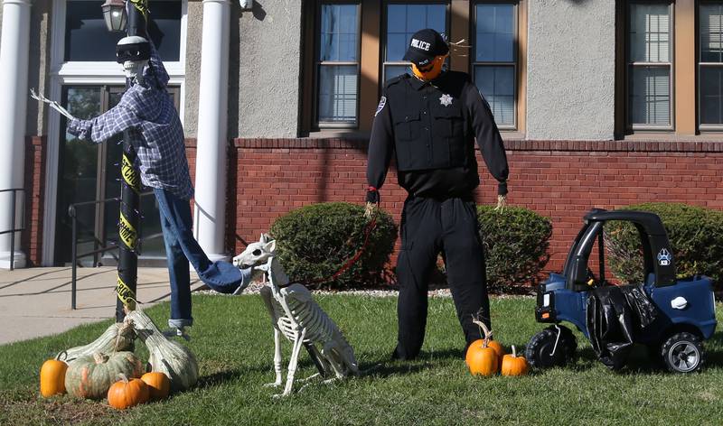 This Halloween display shows a robber being attacked by a skeleton dog while a police officer stands next to a blue Little Tykes car on Tuesday, Oct. 10, 2023 at the Oglesby Police Station.