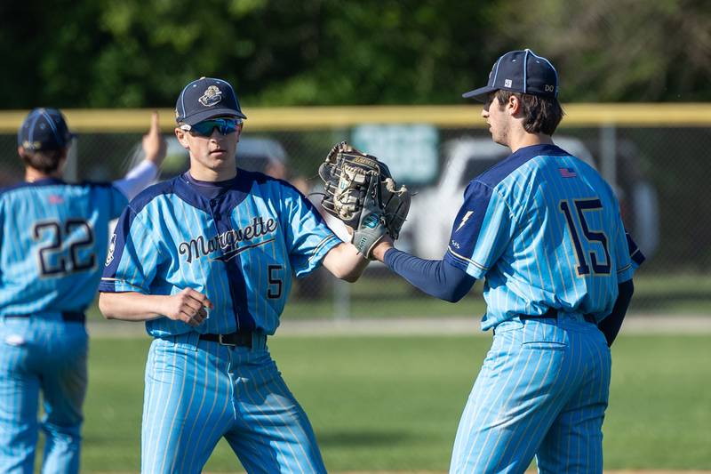 Caden Durdan (5) of Marquette, bumps gloves with teammate Alec Novotney (15) on Thursday, May 8, 2025 at Masinelli Field in Ottawa.