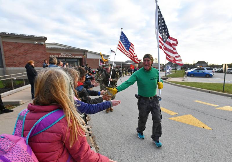 U.S. Navy Veteran Dan Gerber high fives children outside Manteno Elementary School as he leads a group of more than 30 veterans on the 7th annual Veterans Day Military Warriors Run in 2022.