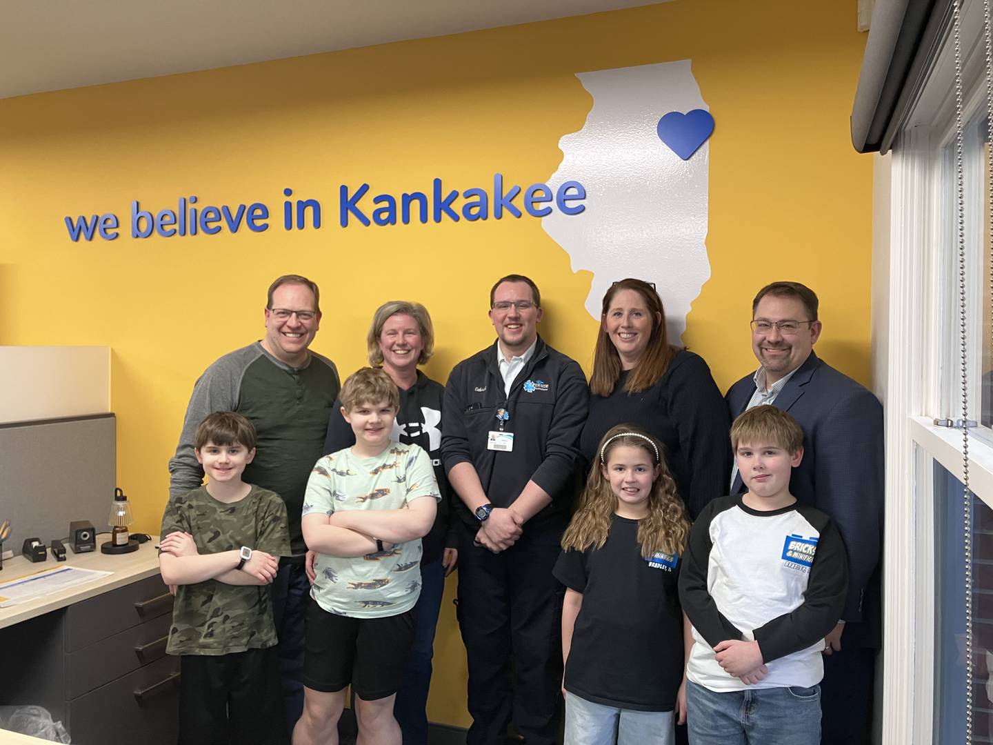 Cory and Christena Estby, back left, of Grant Park, stand with their sons Josiah, 10, and Samuel, 12, front left, and Gabriel, 23, center, as well as Karen and Erik Sorensen, back right, of Beecher and their children Serena, 7, and Carter, 9, at First Financial Bank. The group is opening a Brick & Minifigs business in Bradley this April.