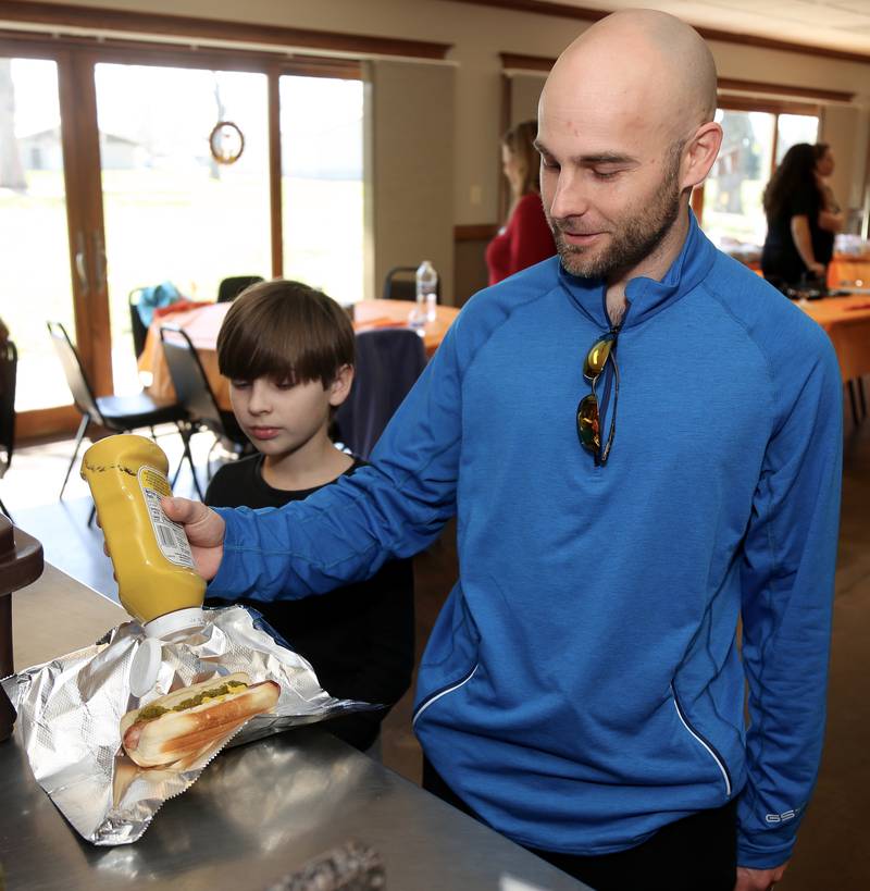 Logan Jaros watches dad Ryan Jaros (neighbors of Frankie Techner) fix his hot dog at the Be the Match Stem Cell Screening and Blood Donation Event at Elburn's Lion's Club that was held for Frankie Techter on Saturday, April 8, 2023.