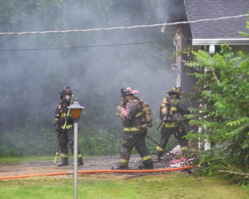 Oregon firefighters exit a charred garage while battling a fire at 540 E. Elizabeth Road on Wednesday, Aug. 20, 2025.